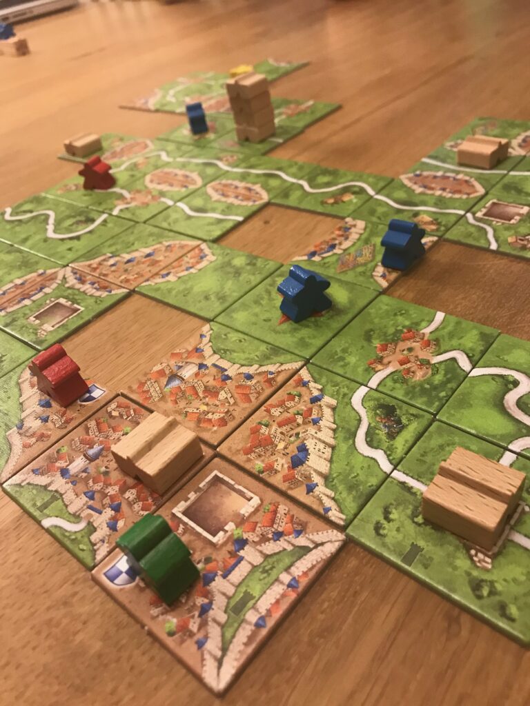 A close up view of some tiles in teh game of Carcassonne. Three of the tiles shown have towers on them with varying numbers of tower floors. Also visible is one tower base without any tower floors added.