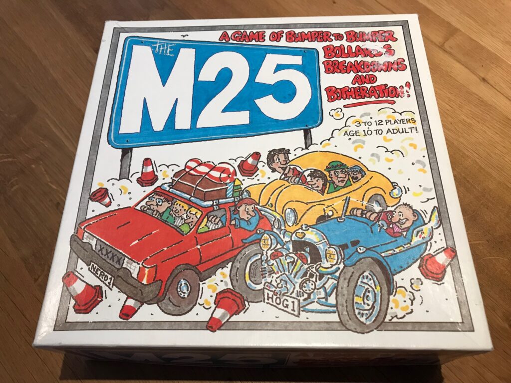 The box for the M25 game showing a cartoon style picture of three cars full of people with comedy number plates (NERD1 and HOG1) and surrounded by bollards going in all directions.