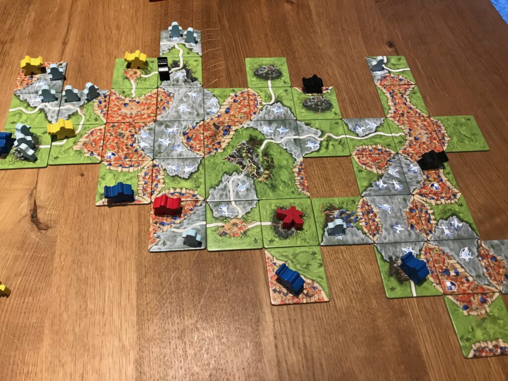 A panned out view of a whole game of Mists over Carcassonne. As well as closed mist banks you can also see open ones with ghosts in them. Also present are three open cemeteries. Two have no ghosts on them whilst one has three.