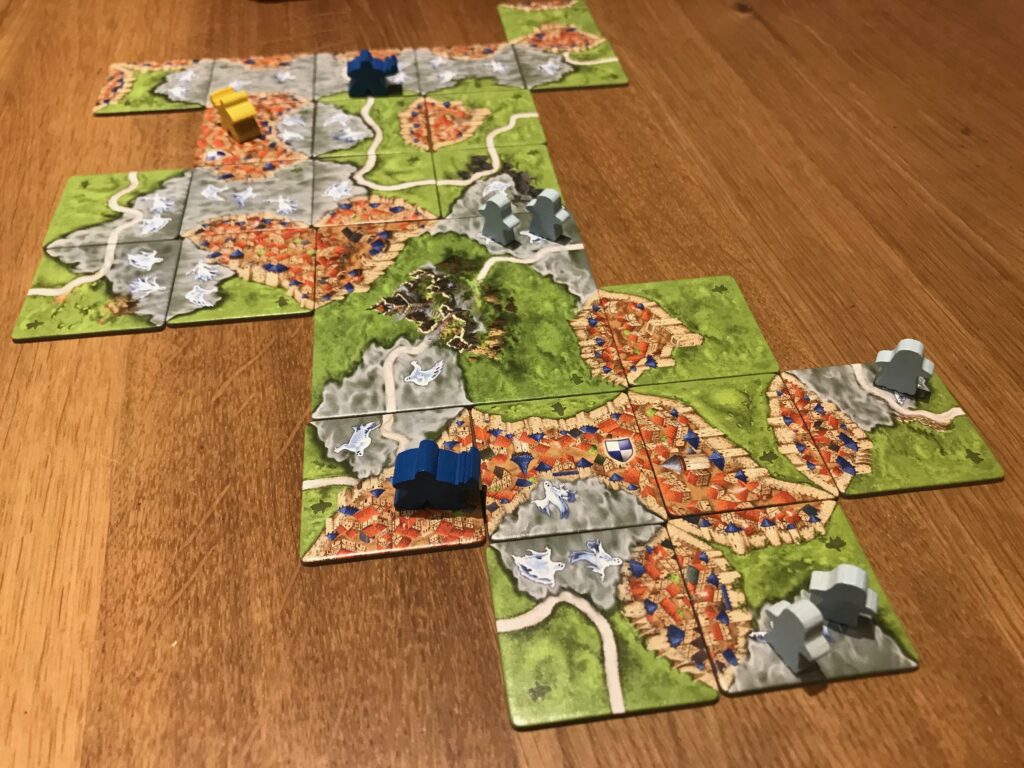 A game of Mists over Carcassonne in play showing several mist banks - some completed and some not. You an see some ghosts in the uncompleted mist and three different guard meeples in cities or on roads.