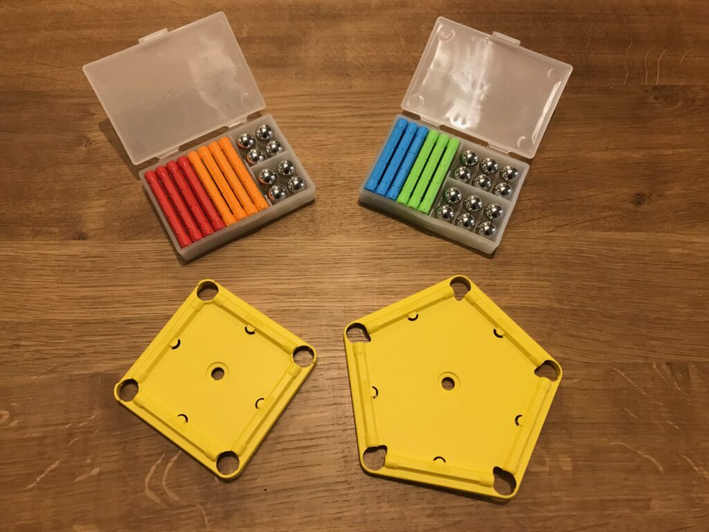 Shown are two plastic storage boxes, open, showing teh magnetic rod and ball contents. Also shown are two plastic base plates - one square and the other a pentagon. They are yellow in colour.