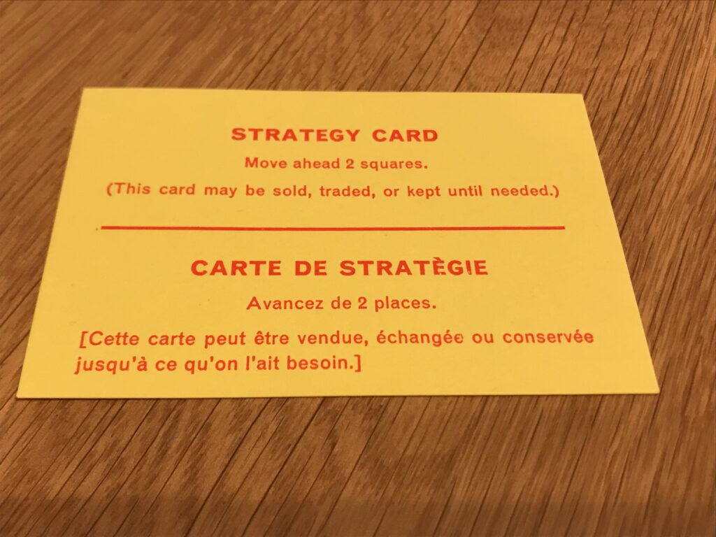 One of the Ulcer cards. It reads as follows: Strategy Card. Move ahead 2 square. (This card may be sold, traded, or kept until needed.) The message is then repeated in French.