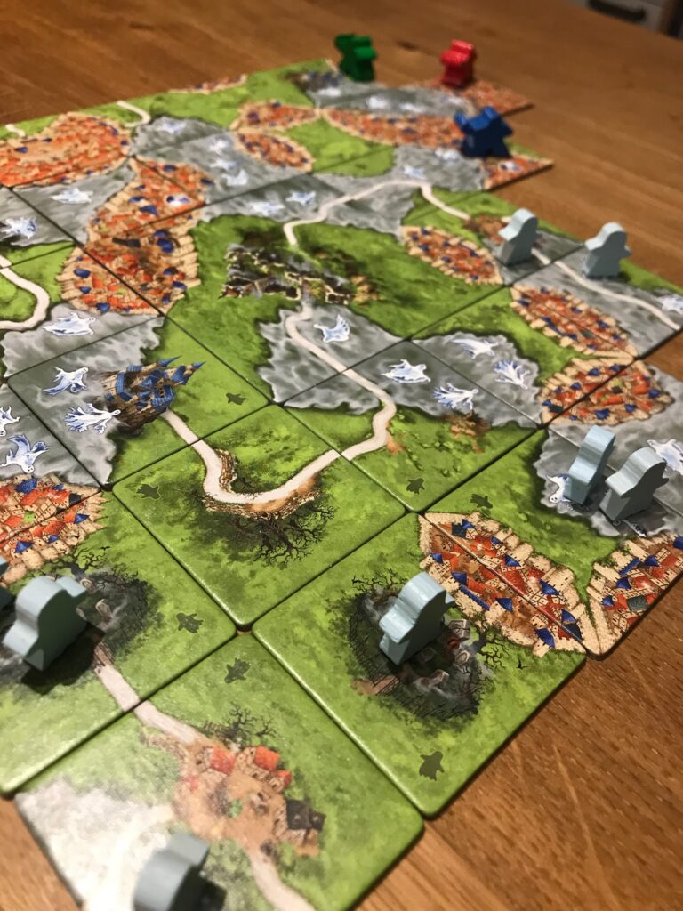 A game in progress showing lots of different tiles containing mist but notable in the foreground are two open cemetery tiles each with one ghost on them.